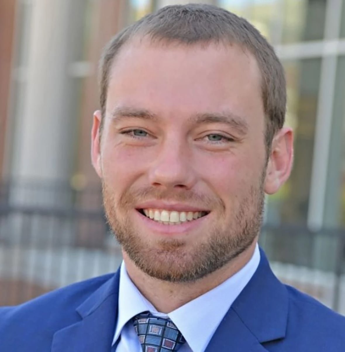 A man smiles in a portrait photograph.