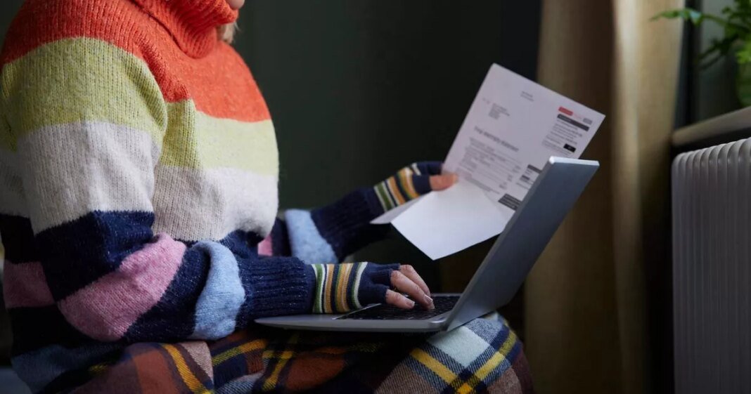 3_woman-in-gloves-with-laptop-and-bill-trying-to-keep-warm-by-radiator-during-cost-of-living-energy-crisis