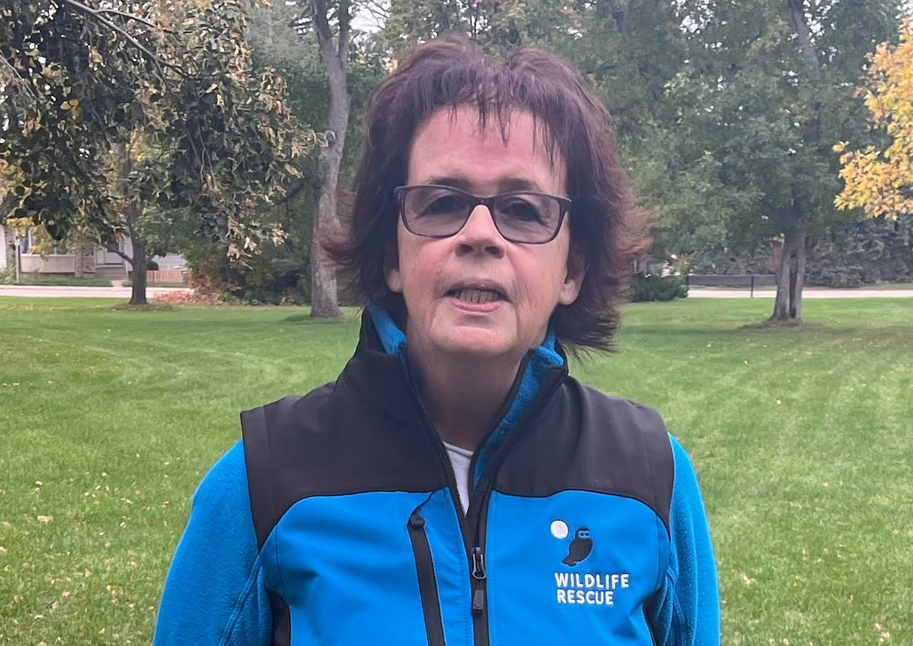 A woman in a park wearing a badge labeled "Wildlife Rescue."